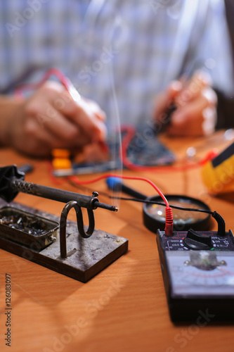 Male hands checking circuit with multimeter