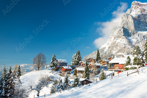 Christmas vacation in Europe. Travel to Switzerland in the winter. Alpine Village in the snow. Traditional houses with red shutters and roofs.