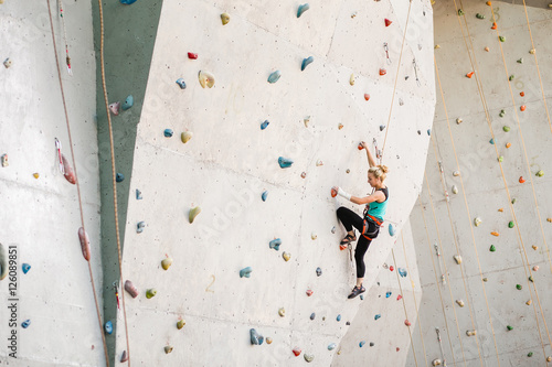 Sporty young woman exercising in a colorful climbing gym
