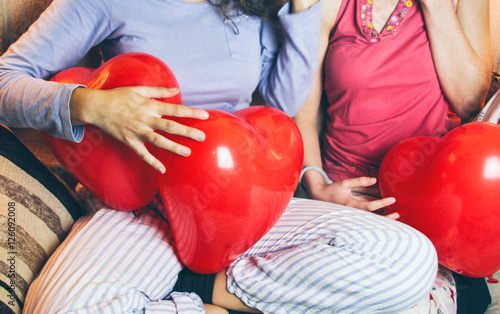 Dos chicas en una fiesta de pijamas con globos con forma de corazón  photo