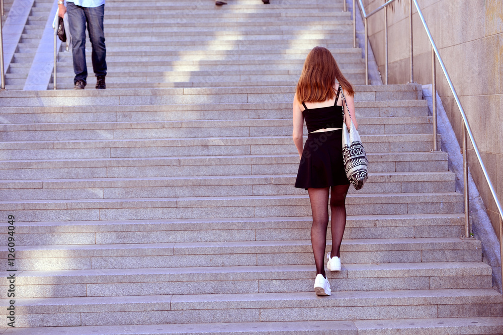 Obraz premium Young adult woman walking up the stairs