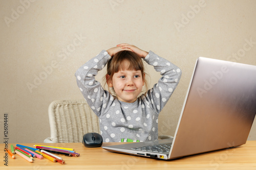 Девочка за компьютером улыбается