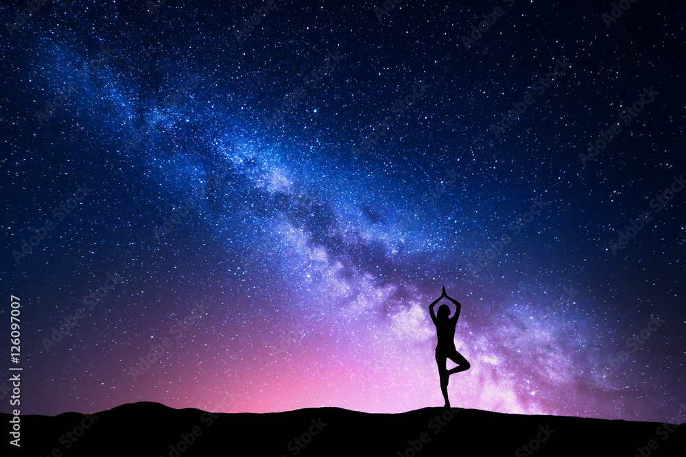 Naklejka Droga Mleczna z sylwetką kobiety stojącej ćwiczącej jogę na górze. Piękny krajobraz z medytacji dziewczyny przed nocnym gwiaździstym niebem z mlecznej. Niesamowita galaktyka. Wszechświat. Podróżować