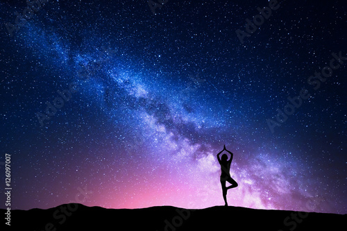 Naklejka Droga Mleczna z sylwetką kobiety stojącej ćwiczącej jogę na górze. Piękny krajobraz z medytacji dziewczyny przed nocnym gwiaździstym niebem z mlecznej. Niesamowita galaktyka. Wszechświat. Podróżować