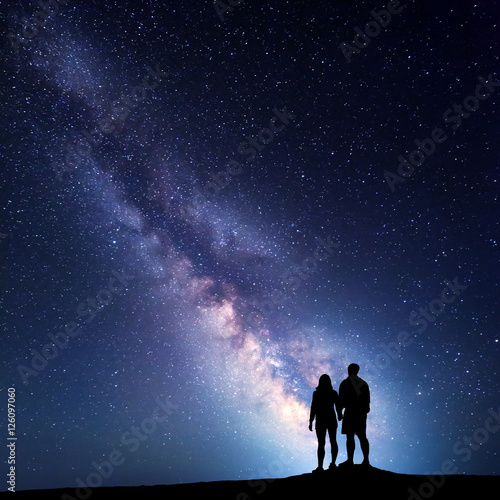 Milky Way with people on the mountain. Landscape with night sky with stars and silhouette of standing man and woman. Milky way with couple. Travelers against beautiful galaxy. Universe