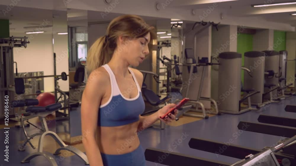 Sportswoman warming up walk texting on mobile phone Sportswoman warming up walk texting on mobile phone