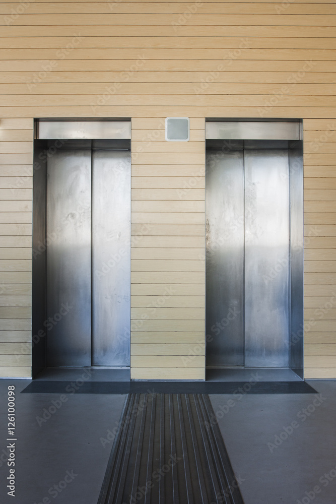 Front view of a modern elevator with closed doors in lobby Front view of a modern elevator with closed doors in lobby