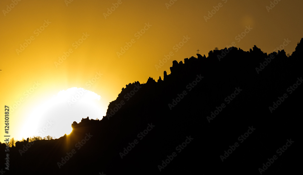 Cross on rocky hills with beautiful sunset