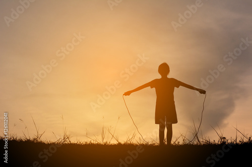 Silhouette young girl rope jumping on the sunset. Time on holiday happy and fun , vintage tone