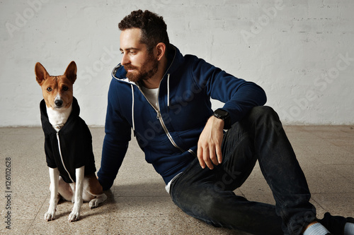 A cute basenji dog and its owner wearing matching outfits sitting on the floor