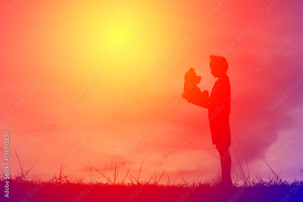 Silhouette a girl with teddy bear on mountain and sky sunset, happy girl in holiday process style vintage tone