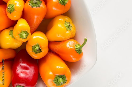 Peperoni gialli rossi e arancioni dentro a ciotola bianca photo