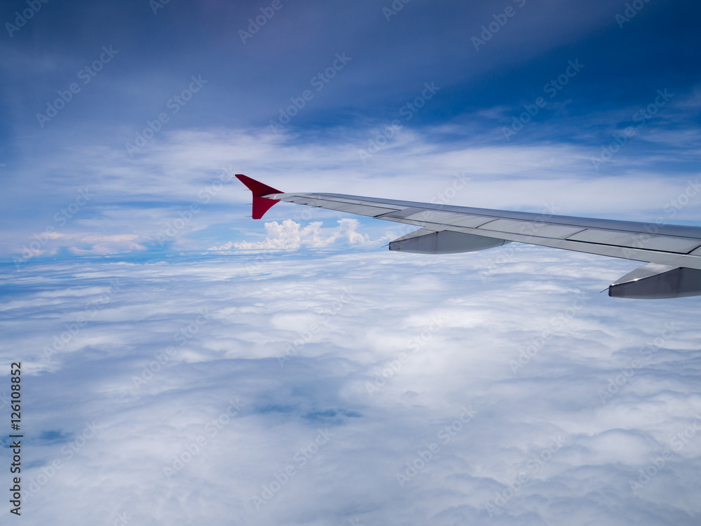 Obraz premium Airplane wing over white cloud and blue sky view from window of airplane while flying over Thailand.