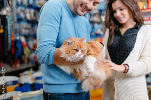 Young couple with their persians cat in pet shop. 