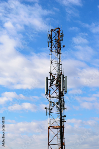 communication tower with mobile telephone antenna on cloudy sky background