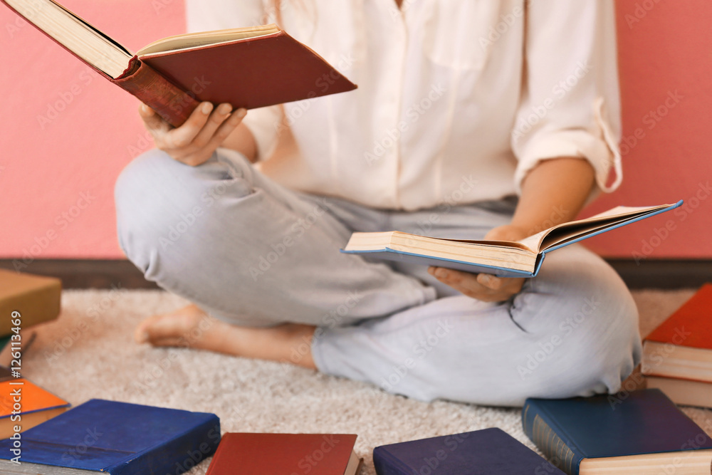 Obraz premium Woman reading book and sitting on a floor on pink background