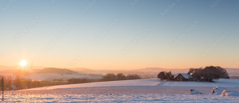 Schneelandschaft mit bedeckter Schneedecke und Gegenlicht bei Sonnenaufgang