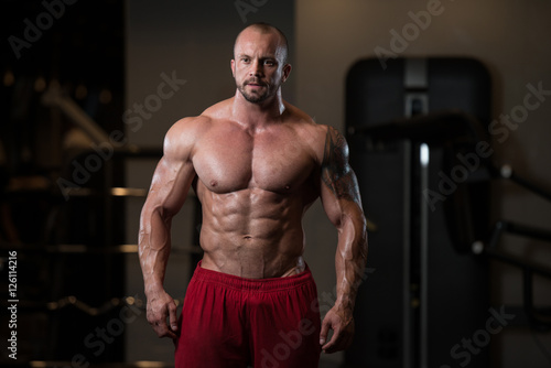 Muscular Man Flexing Muscles In Gym