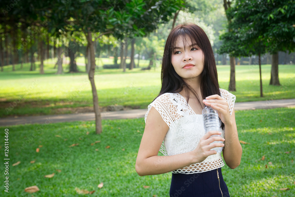 Young beautiful woman wearing white shirts drinking water at su Young beautiful woman wearing white shirts drinking water at su