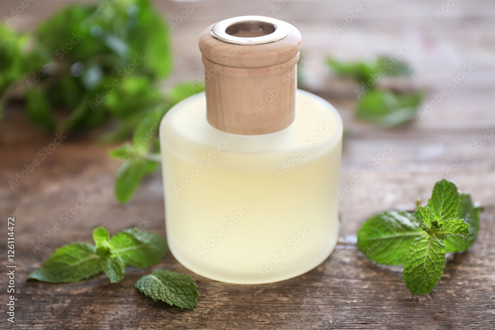 Essential oil with mint on wooden background Essential oil with mint on wooden background