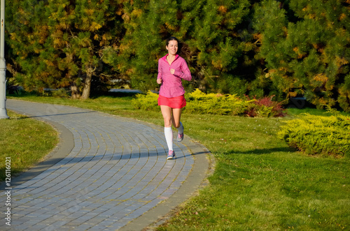 Woman running in autumn park, beautiful girl runner jogging outdoors, training for marathon, exercising and fitness concept
