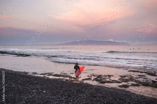 Spain, Tenerife, boy carrying surfboard on the beach at sunset photo