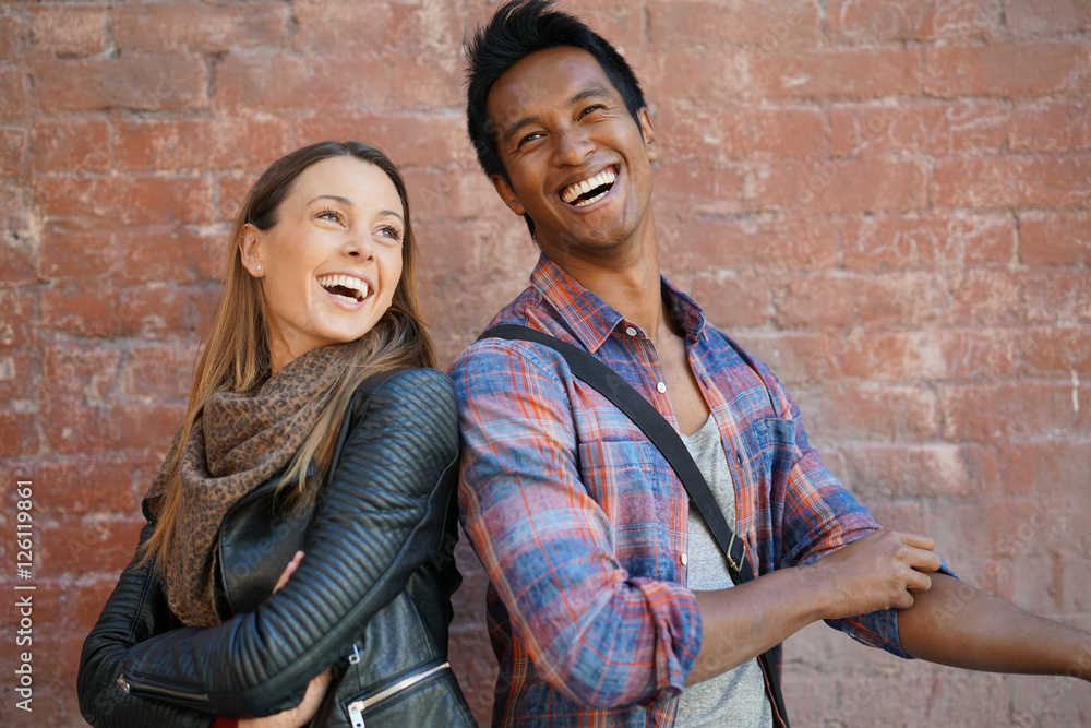 Cheerful couple standing in front of brick wall