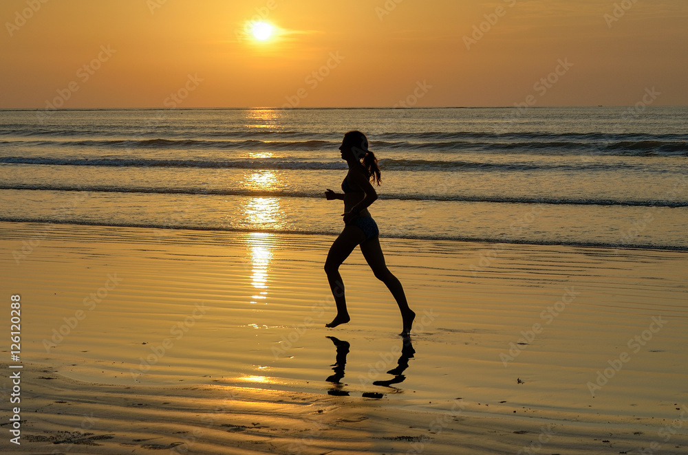 Silhouette of woman jogger running on sunset beach, fitness and healthy life concept
