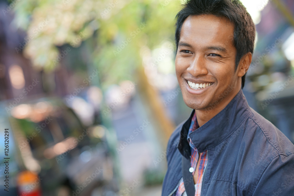 Smiling mixed-raced guy standing in the street Smiling mixed-raced guy standing in the street