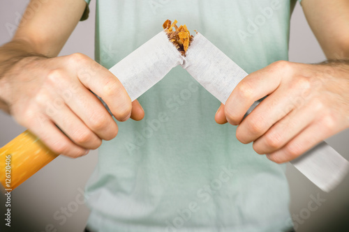 Quit smoking - male smoker breaking giant cigarette