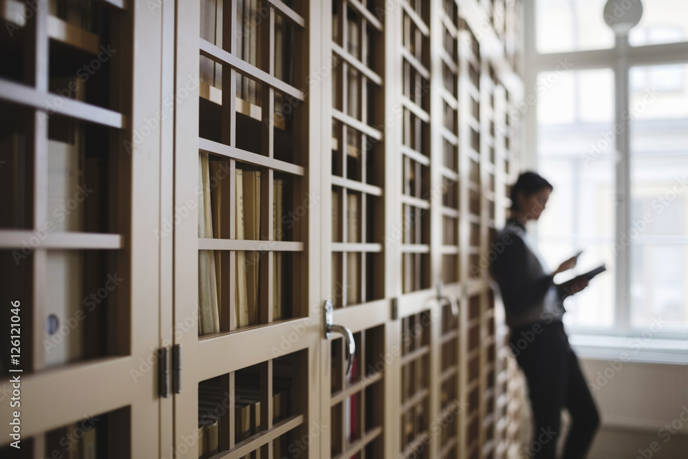 Female lawyer leaning on bookshelf in library Female lawyer leaning on bookshelf in library