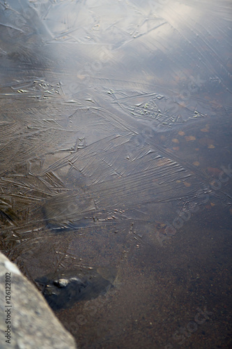 Thin ice. It is transparent and beautiful detailed texture on the water surface.