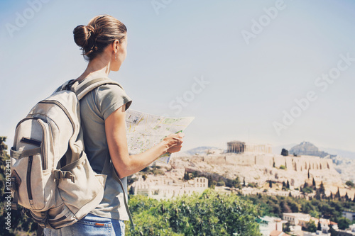 Принти на полотні Back side of traveler girl searching right direction on map in Athens with Acrop