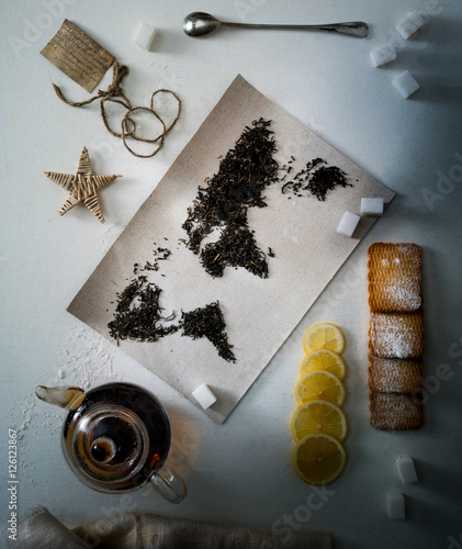 map of the world, lined with tea leaves. Eurasia, America, Australia, Africa. vintage. sugar, note, cracker, spoon. top view. flat lay photo