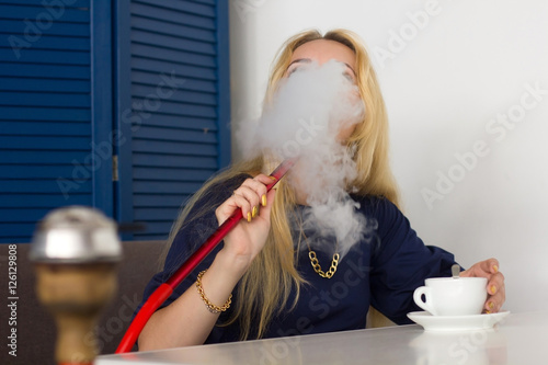 Young girl is smoking hookah in the cafe
