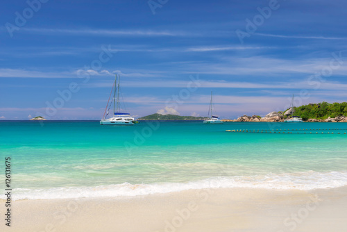 The sea is turquoise and yachts at anchor on tropical island. Fashion travel and tropical beach concept. © lucky-photo