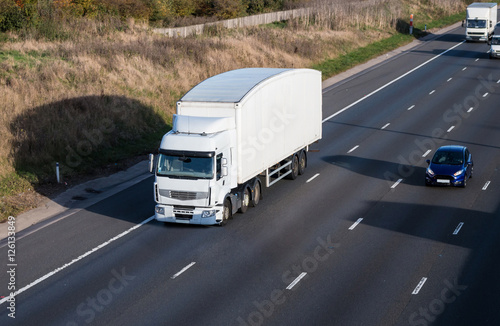 Road transport. White lorry in motion on the motorway