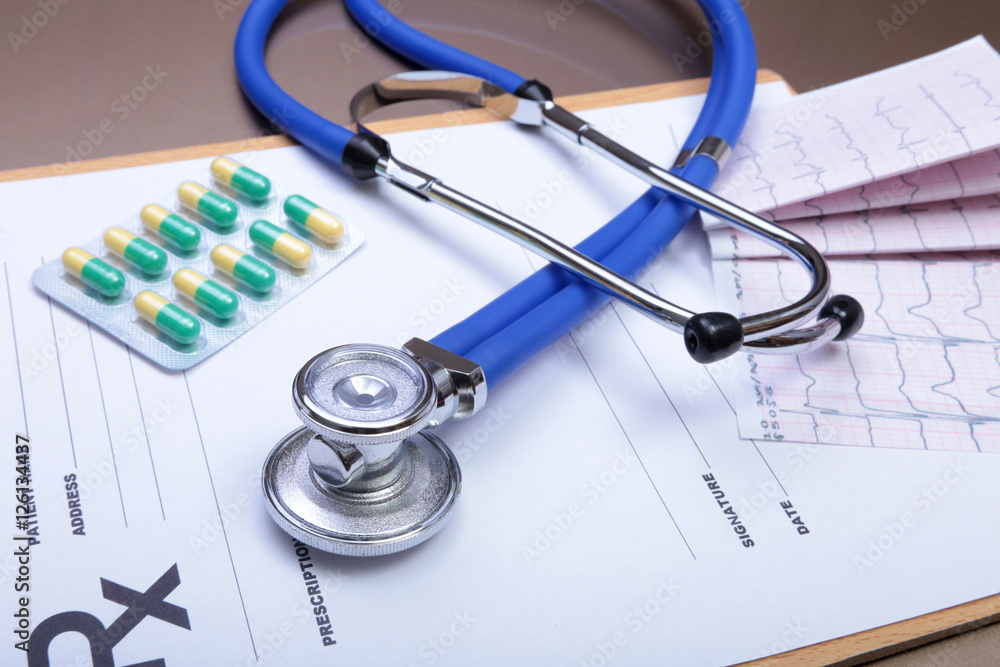 Stethoscope head and silver pen lying on cardiogram clipboard pad. Cardio therapeutist assistance, physician make cardiac physical, pulse beat measure document, arrhythmia idea, pacemaker concept Stethoscope head and silver pen lying on cardiogram clipboard pad. Cardio therapeutist assistance, physician make cardiac physical, pulse beat measure document, arrhythmia idea, pacemaker concept