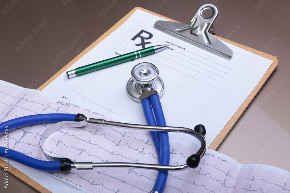 Stethoscope head and silver pen lying on cardiogram clipboard pad. Cardio therapeutist assistance, physician make cardiac physical, pulse beat measure document, arrhythmia idea, pacemaker concept Stethoscope head and silver pen lying on cardiogram clipboard pad. Cardio therapeutist assistance, physician make cardiac physical, pulse beat measure document, arrhythmia idea, pacemaker concept