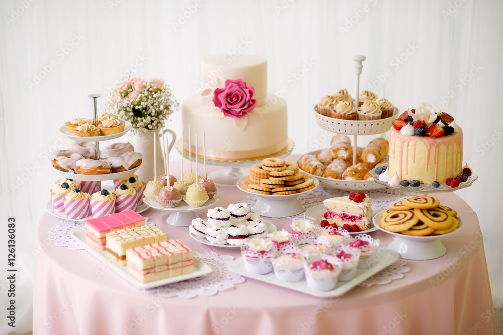 Table with loads of cakes, cupcakes, cookies and cakepops.