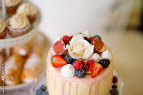 Cake with various berries and meringues on a stand.