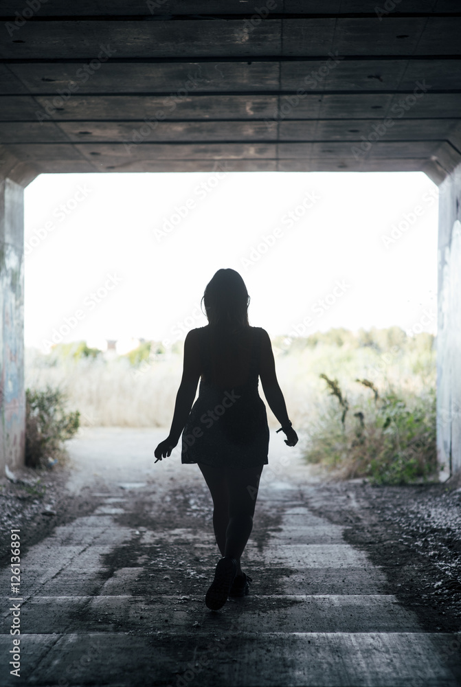 Chica joven caminando a través de un túnel Chica joven caminando a través de un túnel