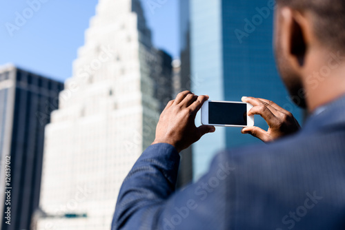 Businessman taking picture of the building with his phone
