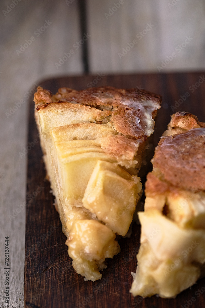 Slice of a french apple cake with vanilla and rum on a cutting board. Wooden background Slice of a french apple cake with vanilla and rum on a cutting board. Wooden background