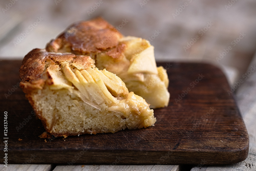Slice of a french apple cake with vanilla and rum on a cutting board. Wooden background. Horizontal Slice of a french apple cake with vanilla and rum on a cutting board. Wooden background. Horizontal