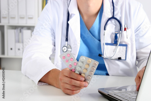 Close-up view of female doctor hand holding bottle with pills and writing prescription. Healthcare, medical  pharmacy concept