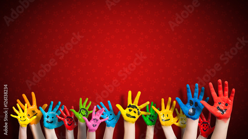 viele angemalte Kinderhände mit Smileys vor weihnachtlichem Hintergrund photo