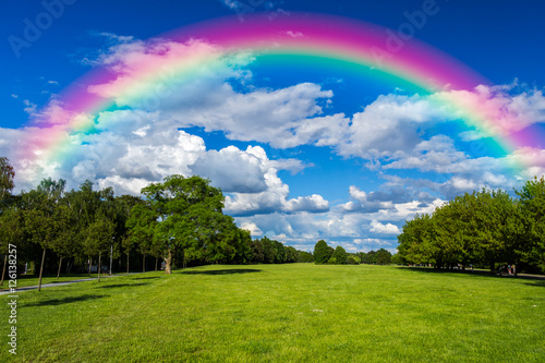 Green grass field, blue sky rainbow, background nature, cloudy park, outdoor for design