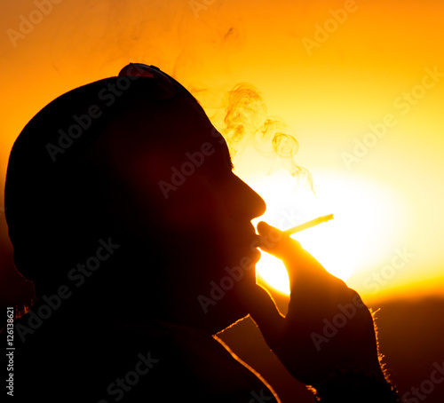 Silhouette of male smokers in the sunset photo