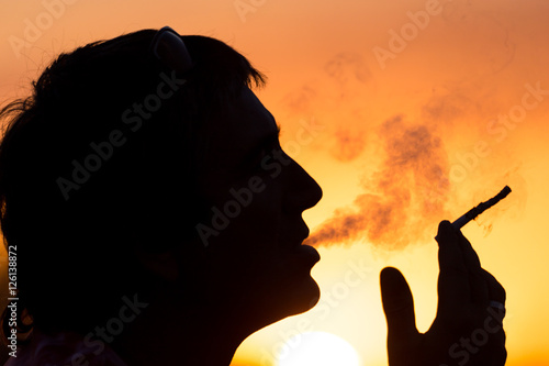 Silhouette of male smokers in the sunset